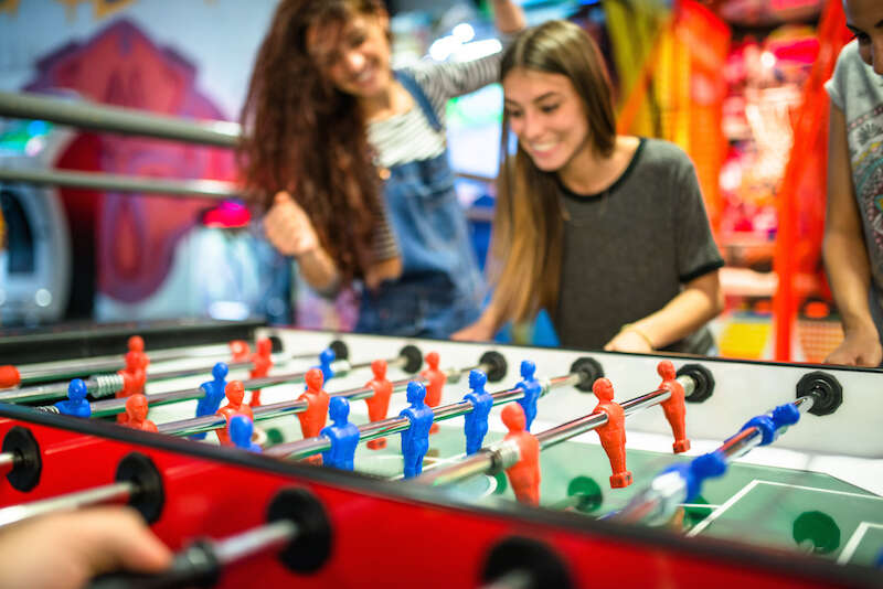 friends playing foosball at the arcade game